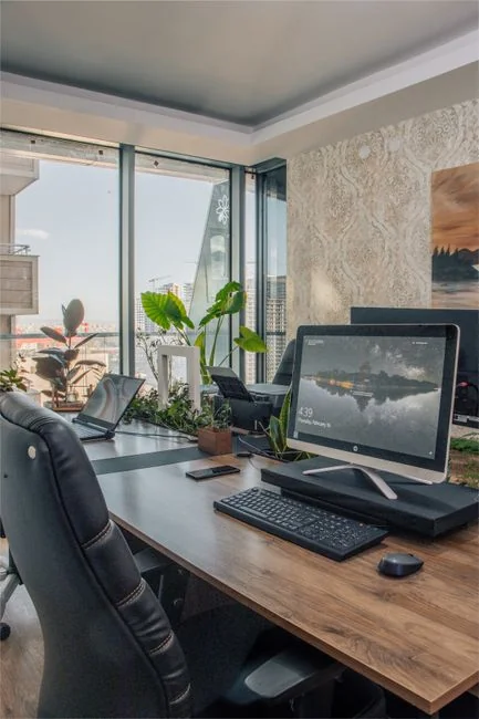 A tidy home office space featuring a wooden desk, chair, broom, and cleaning equipment.